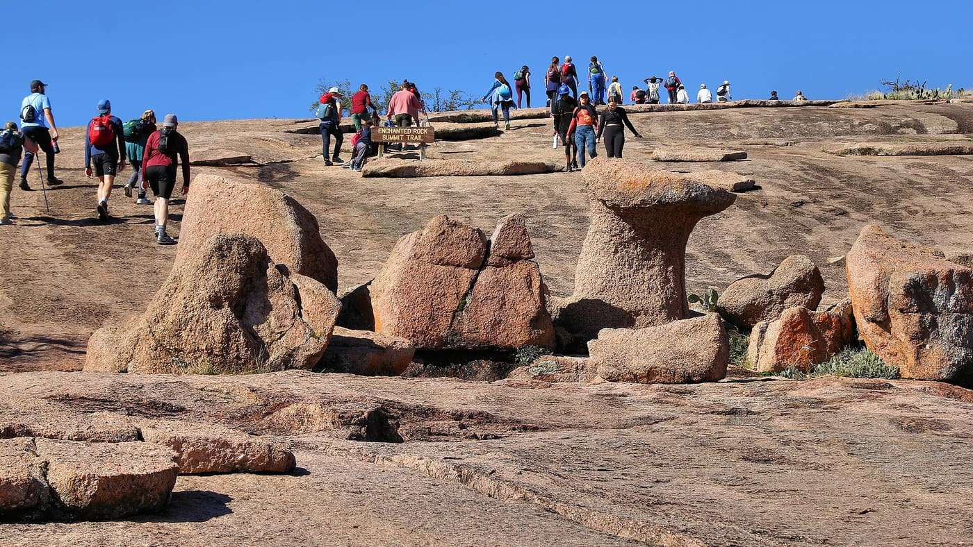 Hikers crossing the bare granite summit between rounded boulders